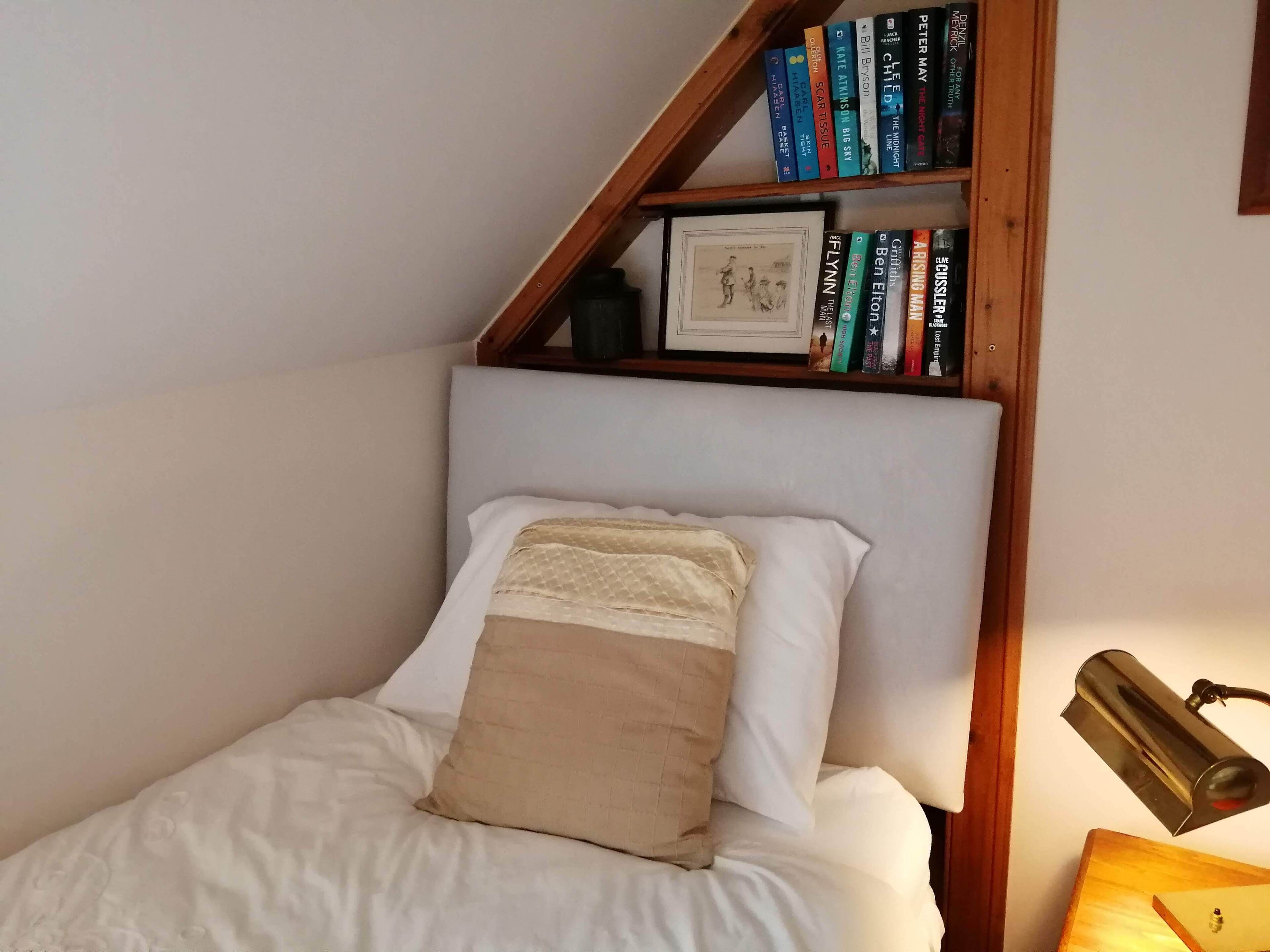 Ein Schlafzimmer mit einem Bett, einem Bücherregal und einer Lampe.