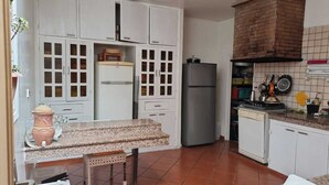 Een keuken met witte kasten, een granieten aanrecht, een koelkast en een bakoven.