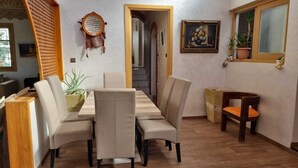 Een eethoek met een houten tafel en stoelen, een bijzettafeltje en een potplant.