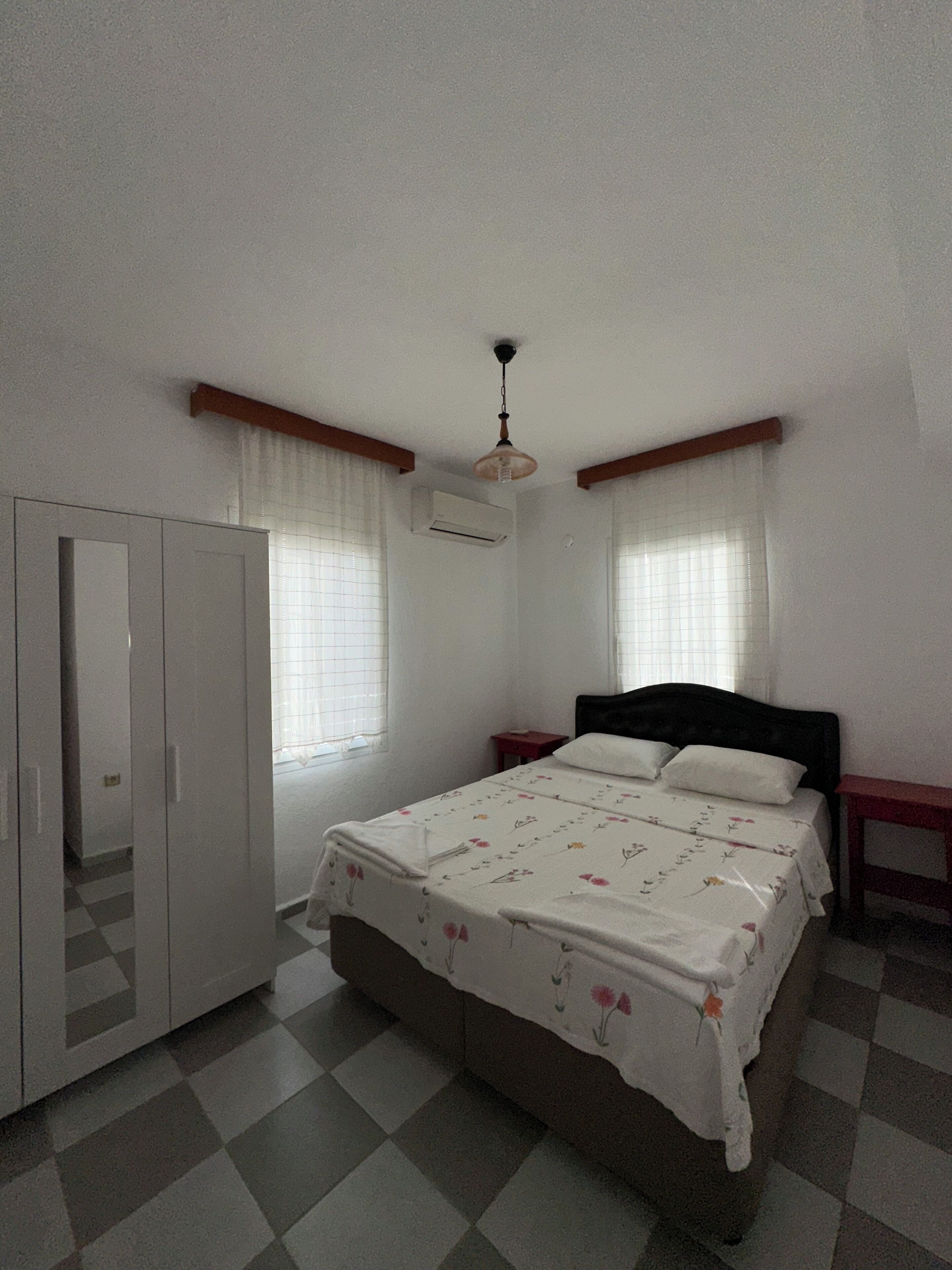 A bedroom with a bed, wardrobe, and a ceiling fan.