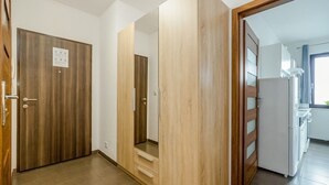 A hallway with wooden doors, a kitchen area with a refrigerator, and a window with curtains. - ShortStayPoland Skierniewicka B156 (Warsaw)