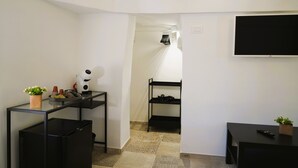 A compact living space with a kitchenette, a TV mounted on the wall, and a small seating area. - Palazzo Lorizzo - Arcuève (Ostuni)