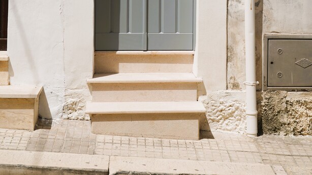 A building entrance with a grey door, a small set of steps, and a number '90' sign. - Palazzo Lorizzo - Arcuève (Ostuni)