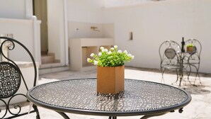 A round metal table with a potted plant in the center, surrounded by metal chairs. - Palazzo Lorizzo - Arcuève (Ostuni)