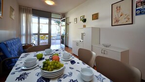 A dining area with a table set for two, featuring a fruit bowl, plates, and cups. - Cozy flat ideal for 6 guests (Bibione)