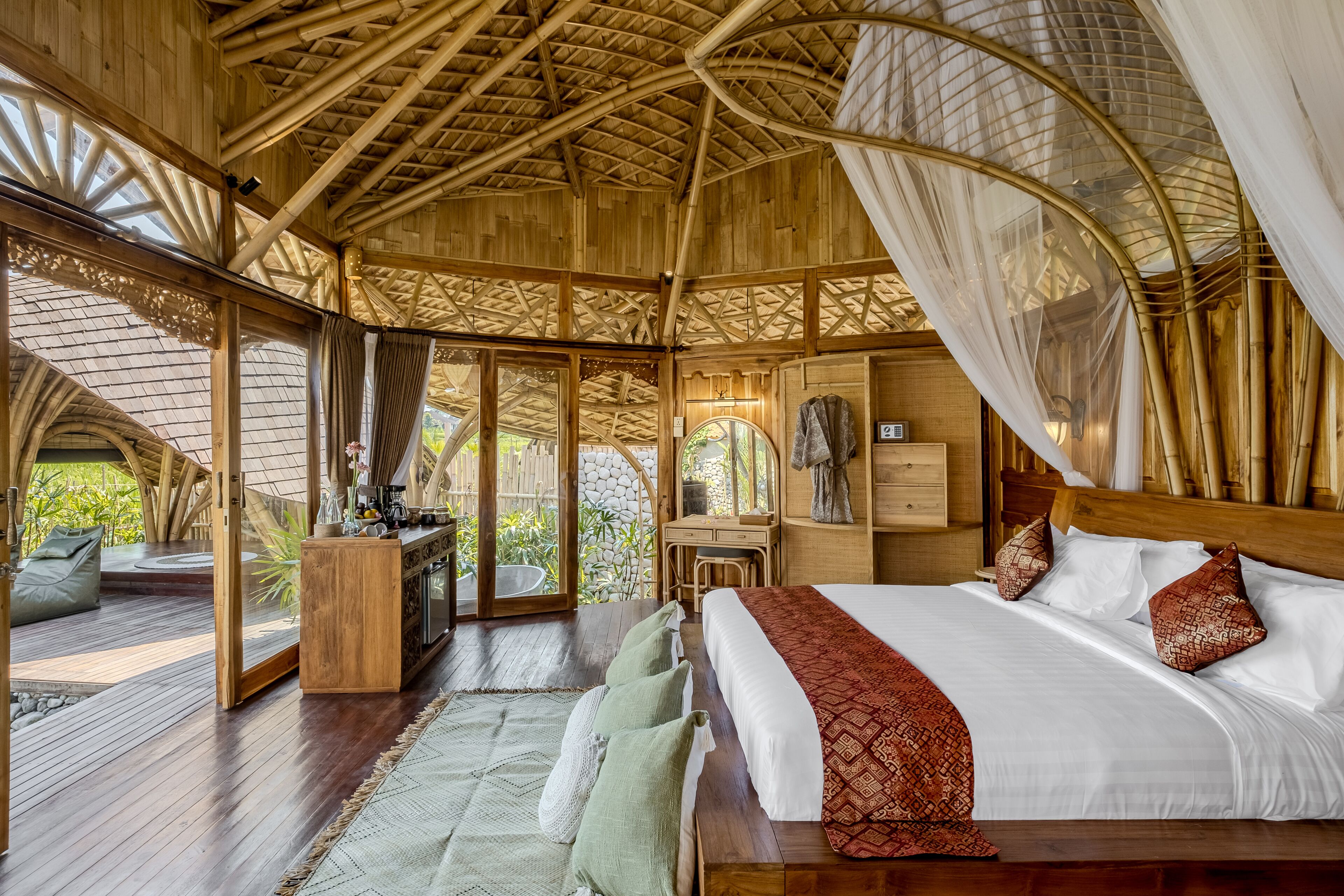 Una habitación amplia con una cama grande, suelo de madera, un escritorio y vistas al exterior.