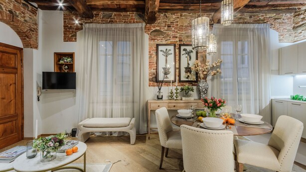 A cozy dining area with a wooden table, cushioned chairs, and a chandelier. - Casa Cinnamon in Lucca (Lucca)