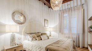 A bedroom with a large bed, two bedside lamps, a mirror, and a bookshelf. - Casa Cinnamon in Lucca (Lucca)