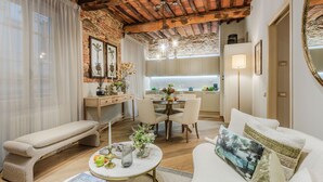 A cozy living room with a bench, a sofa, and a dining table with chairs. There is a kitchen area visible through an open door. - Casa Cinnamon in Lucca (Lucca)