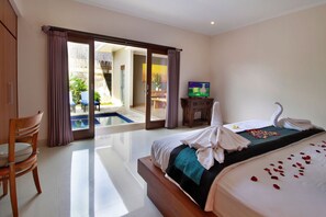 A hotel room with a bed, a TV, a wooden chair, and a view of a pool and outdoor area. - Belvilla Wanderlust Central UbudNearTiti Batu Ubud Club (Ubud)