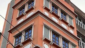 Ein mehrstöckiges Gebäude mit roter Fassade, mehreren Balkonen und traditionellen architektonischen Details.