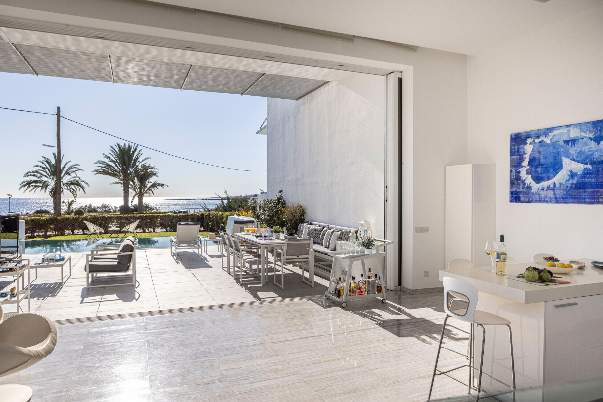 A modern outdoor living area with a pool, seating, and a bar.