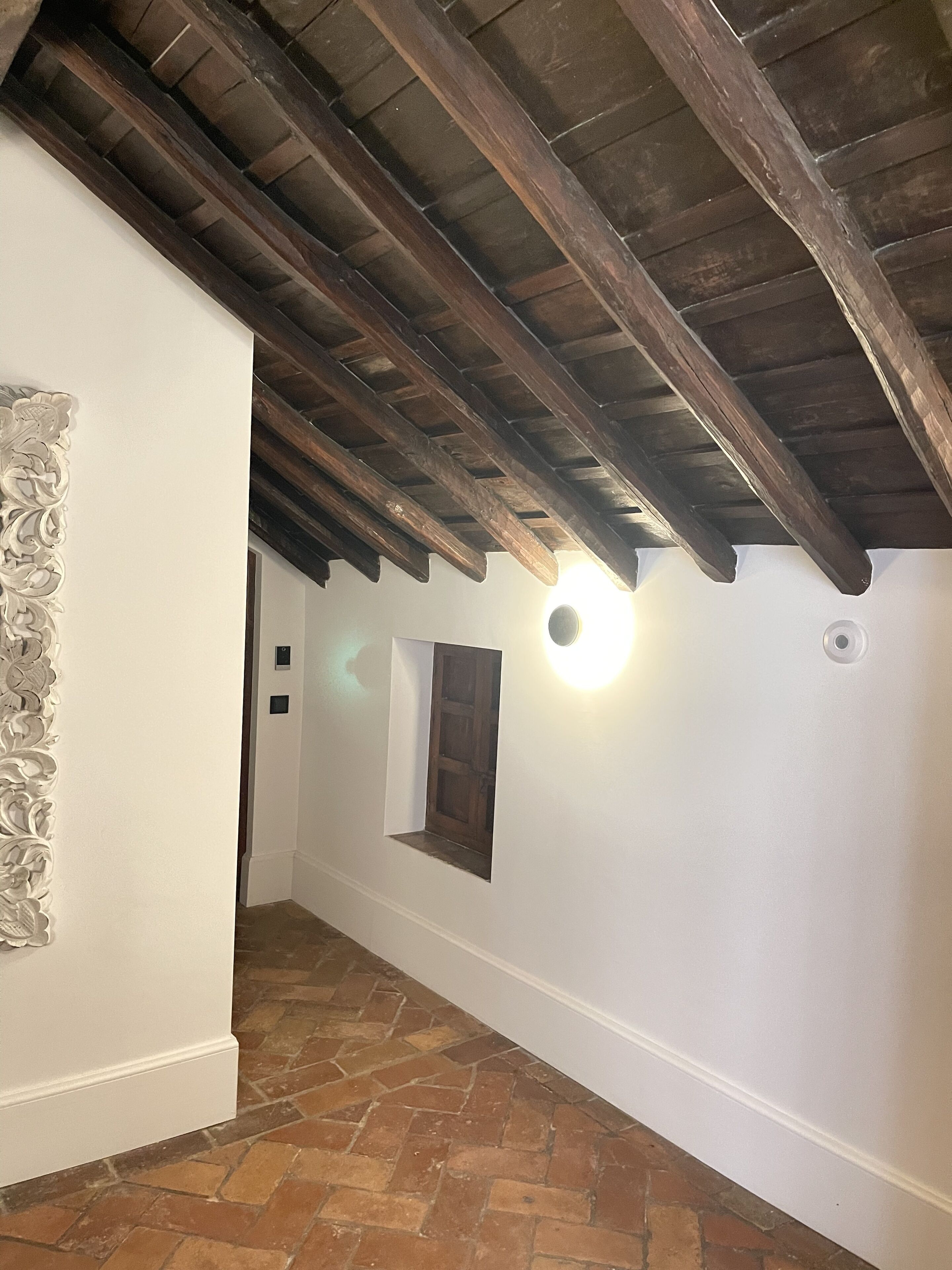 Ein Korridor mit einer gewölbten Decke, einem kleinen Fenster und einer Wandleuchte.