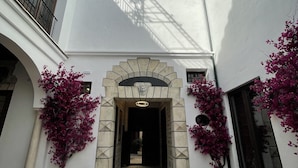 Un patio con un arco central, rodeado de muros blancos y un suelo de baldosas.