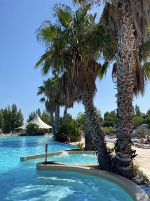 Una piscina con palmeras y una sombrilla.