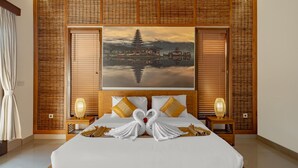 Een hotelkamer met een groot bed, een schilderij van een pagode en een zwaan van handdoeken.