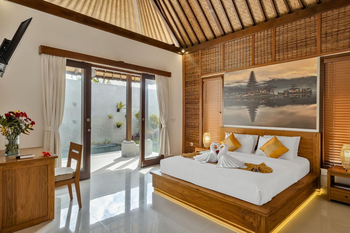 A spacious bedroom with a large bed, wooden headboard, and a scenic wall mural.