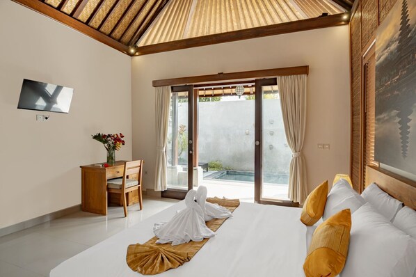 Habitación de hotel con cama, escritorio, silla, televisión y vistas al exterior.