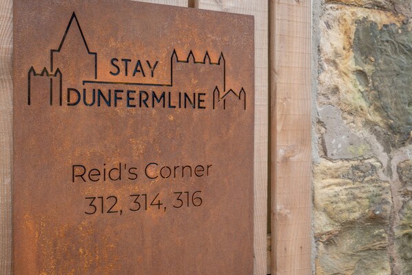 A sign with the text "DUNFERMLINE" and "Reid's Corner" along with phone numbers.
