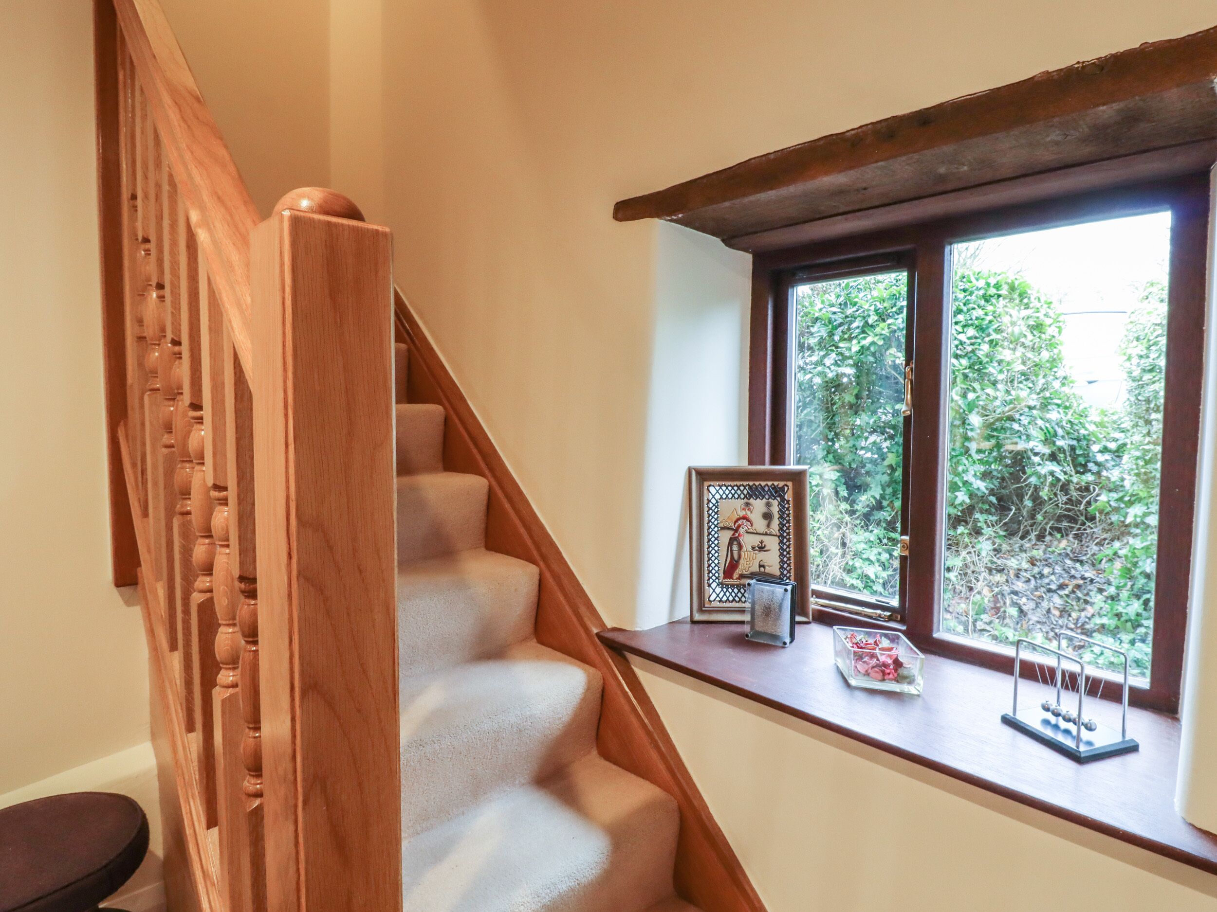 Una escalera de madera con un ventanal arriba.