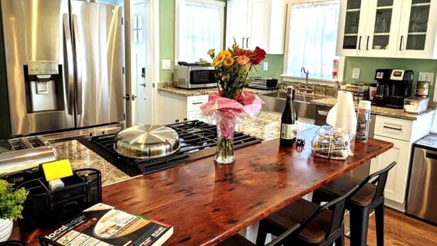 A modern kitchen with stainless steel appliances, a wooden island, and a vase with flowers. - Walkable Elmwood Cottage, No Chores 2Bath 2BR 2Car (Buffalo)