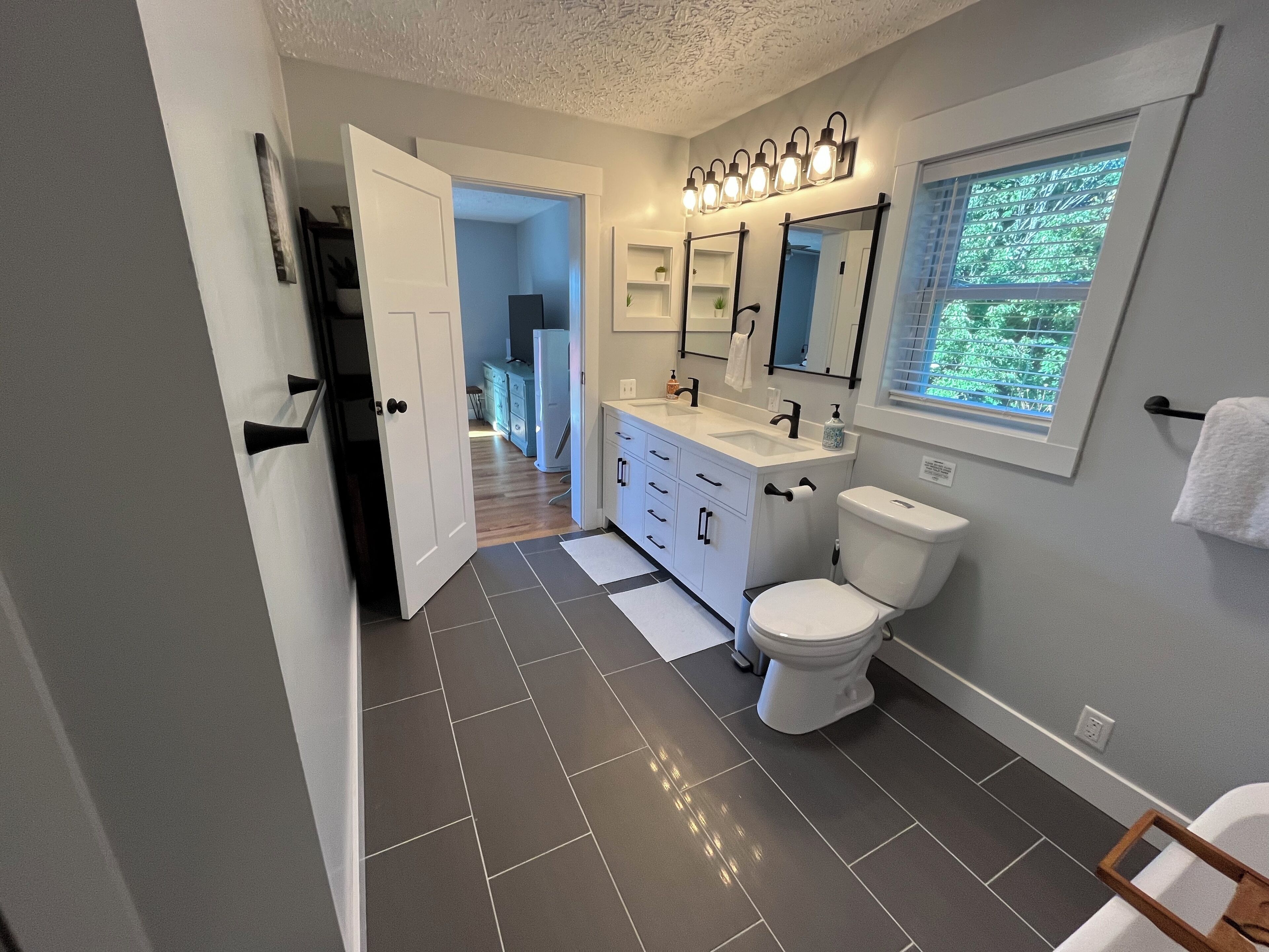 Une salle de bain moderne avec un meuble-lavabo blanc, des toilettes et un grand miroir.