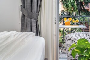 Ett hotellrum med en säng, en balkong med ett bord och utsikt över grönområden.