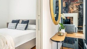 Un dormitorio moderno con cama, mesita de noche y un espejo grande.