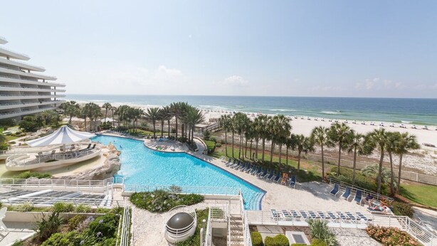 A resort with a large swimming pool, beach access, and a view of the ocean.