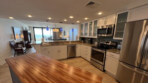 A modern kitchen with stainless steel appliances, white cabinetry, and a wooden island.
