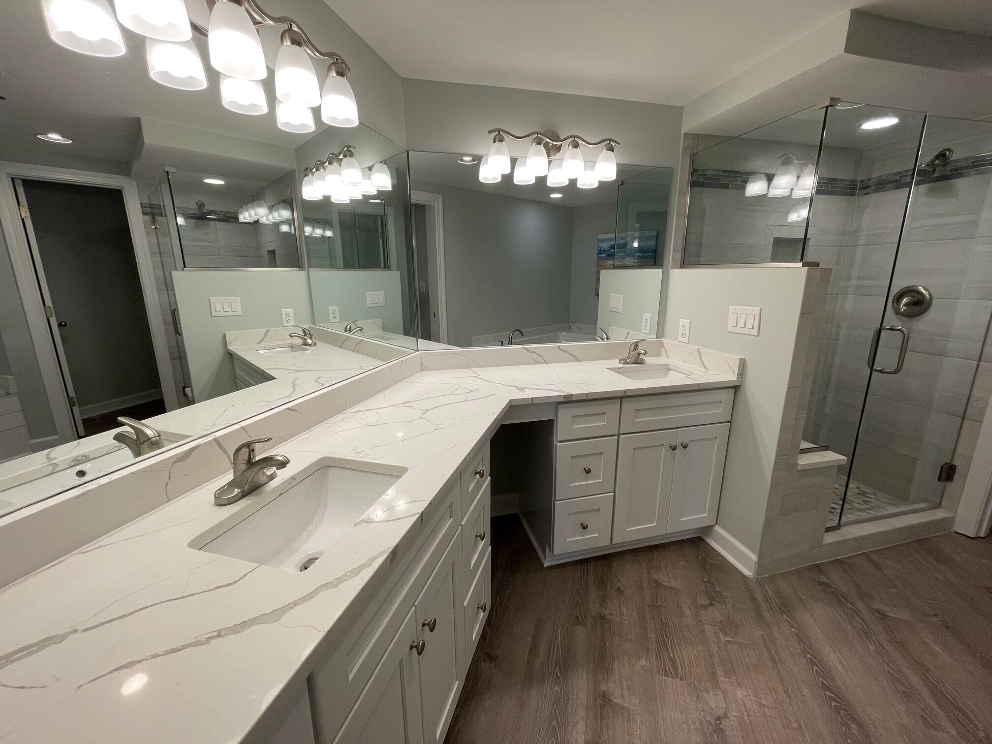 A modern bathroom with a large mirror, two sinks, a shower, and a walk-in shower.