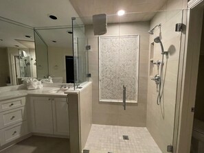 Enjoy a refreshing shower in this bathroom featuring a walk-in shower with a glass door and herringbone tile pattern.
