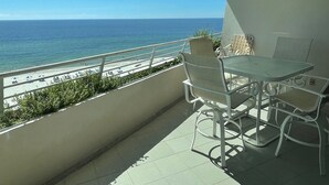 A balcony with a view of the ocean, a table, and chairs. - Gulf Front Condo With Stunning Views! (Pensacola)