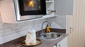 A kitchen with a microwave, sink, and a Winnie the Pooh figurine. - Surebillionaire Home Deluxe Queen Studio (London)