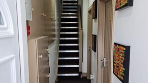 A narrow hallway with a black and white striped staircase leading to a door at the end. - Surebillionaire Home Deluxe Queen Studio (London)