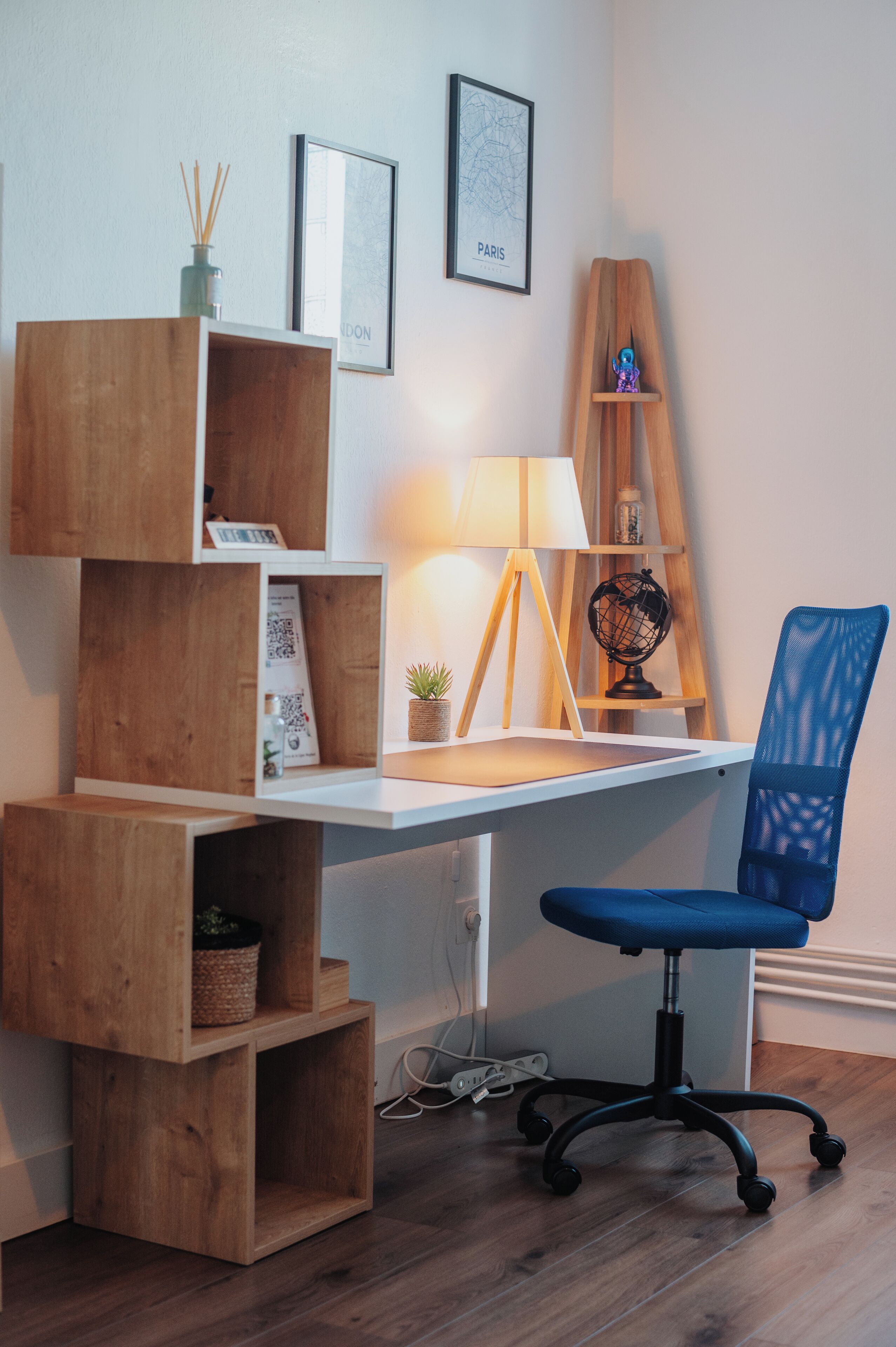 A wooden desk with a lamp, a globe, and a blue chair.