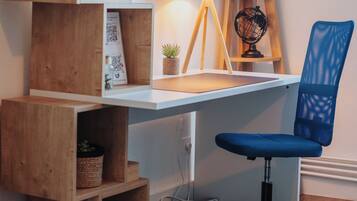 A wooden desk with a lamp, a globe, and a blue chair.