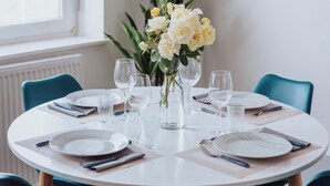 A round dining table with white plates, cutlery, and glasses, surrounded by teal chairs. - Le Rêve Bleu (Thionville)