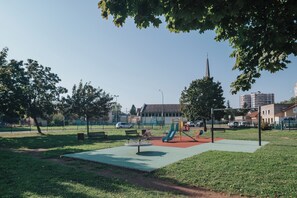 Ein Park mit Spielgeräten, Bänken und Bäumen.