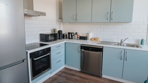 A modern kitchen with stainless steel appliances, light blue cabinets, and white subway tiles. - Le Rêve Bleu (Thionville)