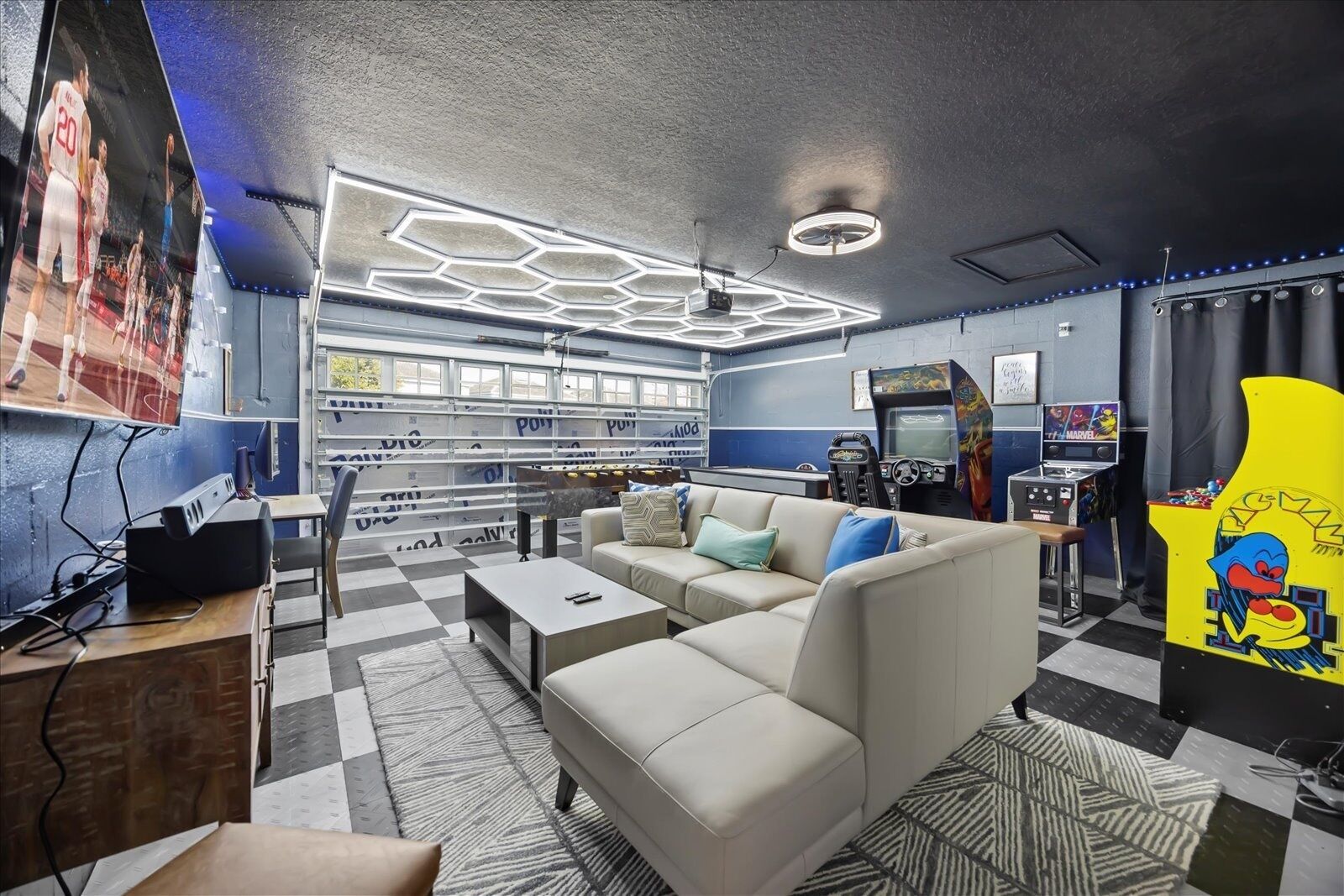 Eine moderne Lounge mit Schachbrettfußboden, einer Couch, einem Couchtisch und Spielautomaten.