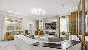 A modern living room with a white sofa, a yellow armchair, a coffee table, and a flat-screen TV mounted on the wall.