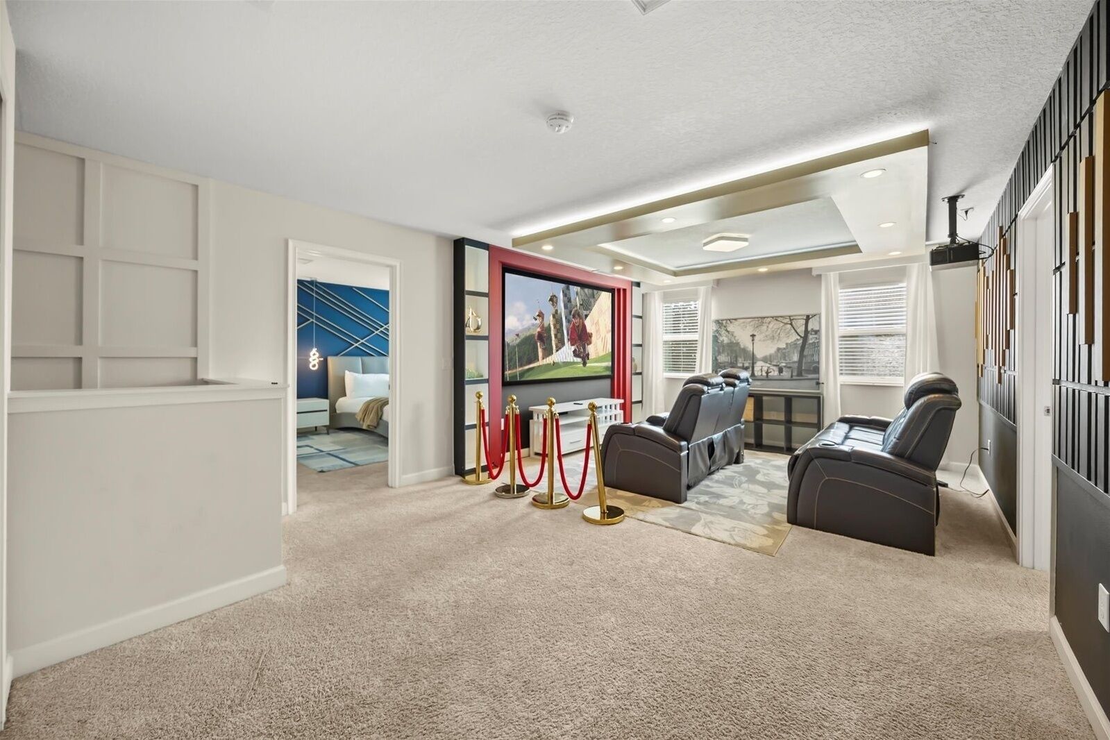 A home theater room with a large screen, comfortable seating, and a carpeted floor.