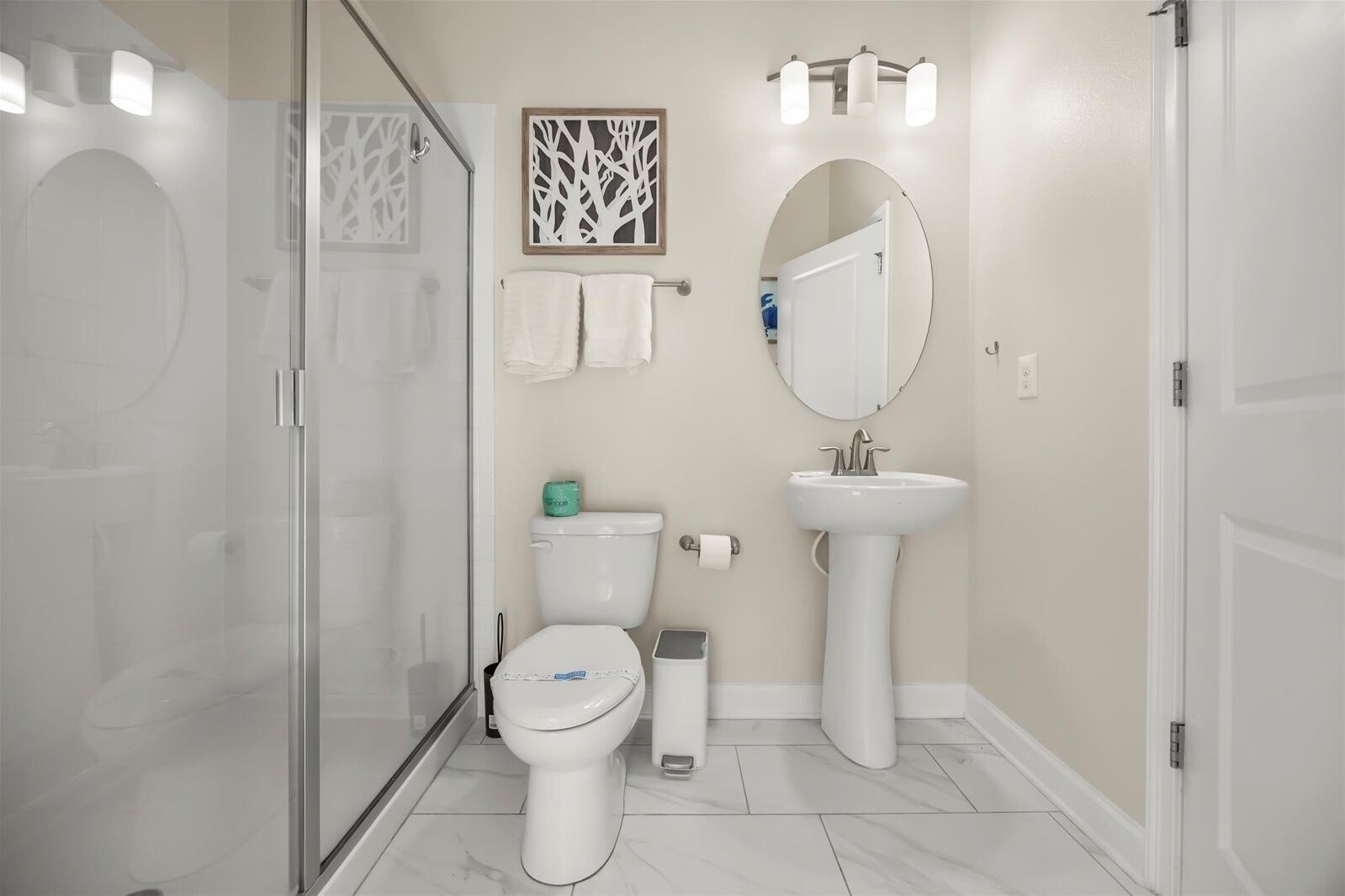Un bany modern amb una dutxa de vidre, un vàter, un lavabo i un mirall.