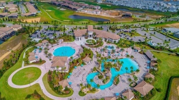 An aerial view of a resort with multiple swimming pools, golf courses, and residential buildings.