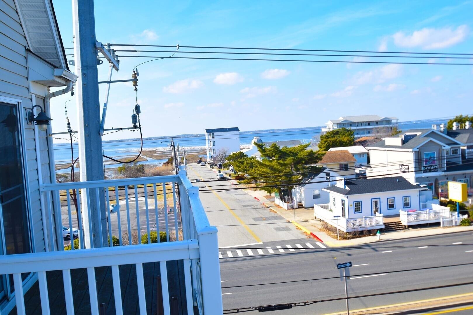 Eine Küstenstraße mit Blick aufs Meer, ein weißes Gebäude mit Balkon und ein kleines Haus mit Veranda.