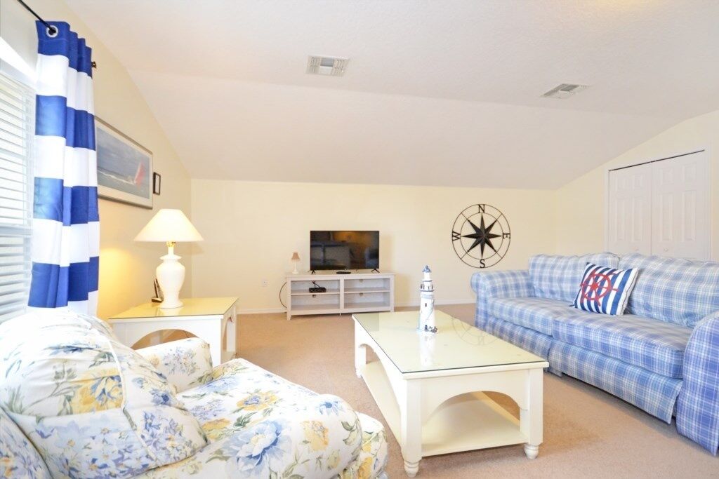 A living room with a sofa, a coffee table, a TV, and a wall clock.