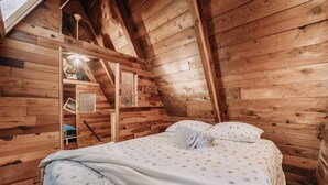 A cozy wooden cabin bedroom with a bed, a small table, and a window. - 54sl - Hot Tub - Pets Ok - Sleeps 4 2 Bedroom Cabin by RedAwning (Deming)