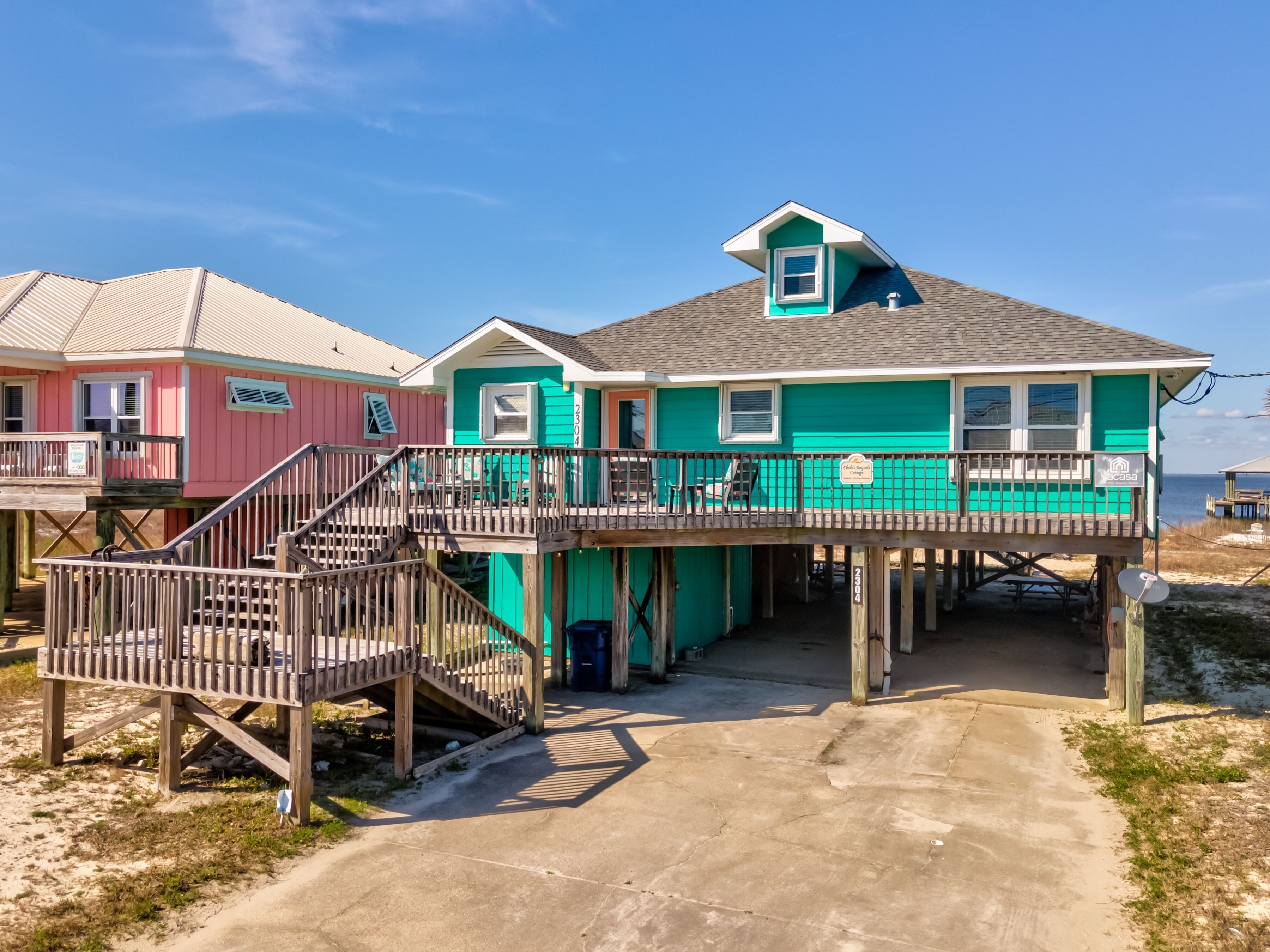 A beachfront property with a multi-level deck, a covered outdoor seating area, and a view of the ocean.