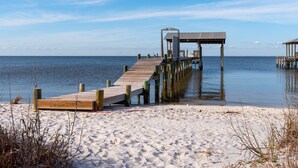 A wooden pier extending into calm waters, leading to a covered structure. - Chele's Bayside Cottage - 2304 Island Shores Dr 4 Bedroom Home by RedAwning (Dauphin Island)